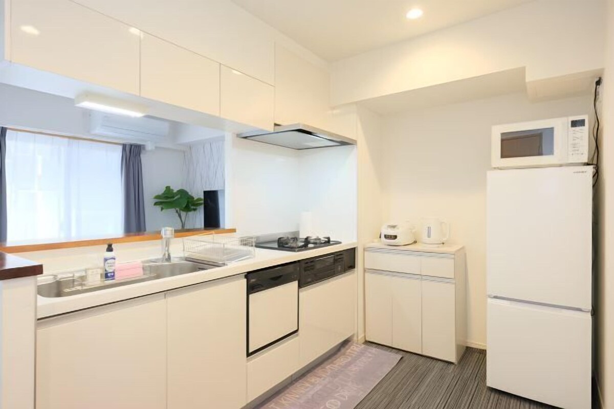A compact kitchen with a microwave, a small refrigerator, a sink, and a dishwasher.