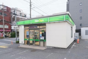 A small, single-story building with a green and white facade, a storefront, and a visible entrance. - Ito House (Tokyo)