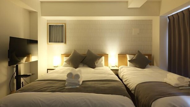 Une chambre d’hôtel avec deux lits, un téléviseur à écran plat et une petite table.
