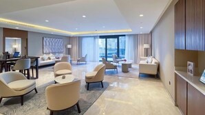 A modern hotel lobby with a spacious layout, including a seating area with sofas and armchairs, a dining area, and a reception desk. - bnbme Luxury Apt Pool w/ Burj Khalifa Views (Dubai)