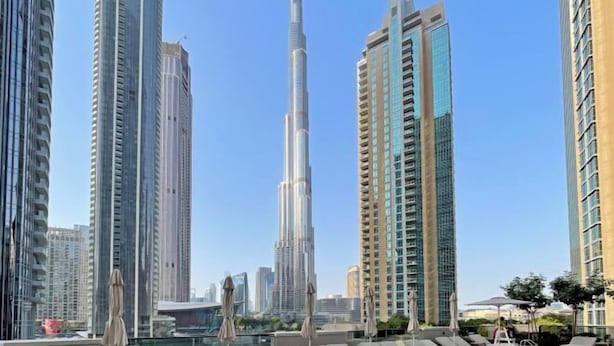 A rooftop pool area with lounge chairs and umbrellas, surrounded by high-rise buildings, including a prominent skyscraper in the background. - bnbme Luxury Apt Pool w/ Burj Khalifa Views (Dubai)