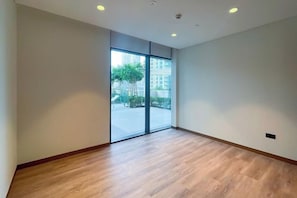 Une pièce dotée d’une grande porte-fenêtre coulissante, d’un plancher en bois et de spots encastrés au plafond.