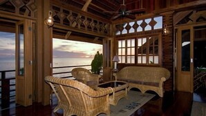 A room with wicker furniture, a ceiling fan, and a view of the ocean. - Sipadan Mabul Resort Semporna (Semporna)
