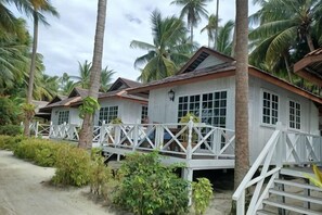 A row of white wooden cabins with balconies, surrounded by palm trees and greenery. - Sipadan Mabul Resort Semporna (Semporna)