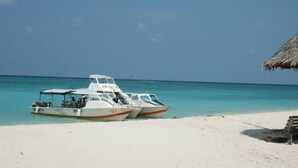 A beach with two boats parked near a thatched-roof structure. - Sipadan Mabul Resort Semporna (Semporna)