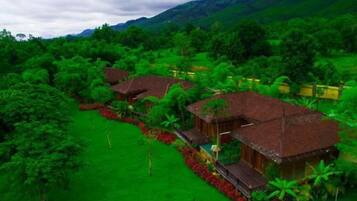 A cluster of traditional-style buildings surrounded by lush greenery and hills in the background.
