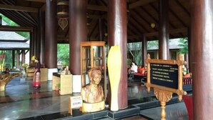 A lobby with a wooden ceiling, large columns, a reception desk, and a sign listing amenities.