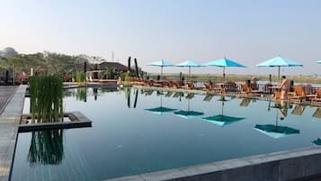 A swimming pool with lounge chairs and umbrellas.
