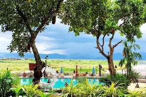 A pool area with a hammock, trees, and a view of the beach. - Aureum Palace Hotel and Resort Inle (Taunggyi)