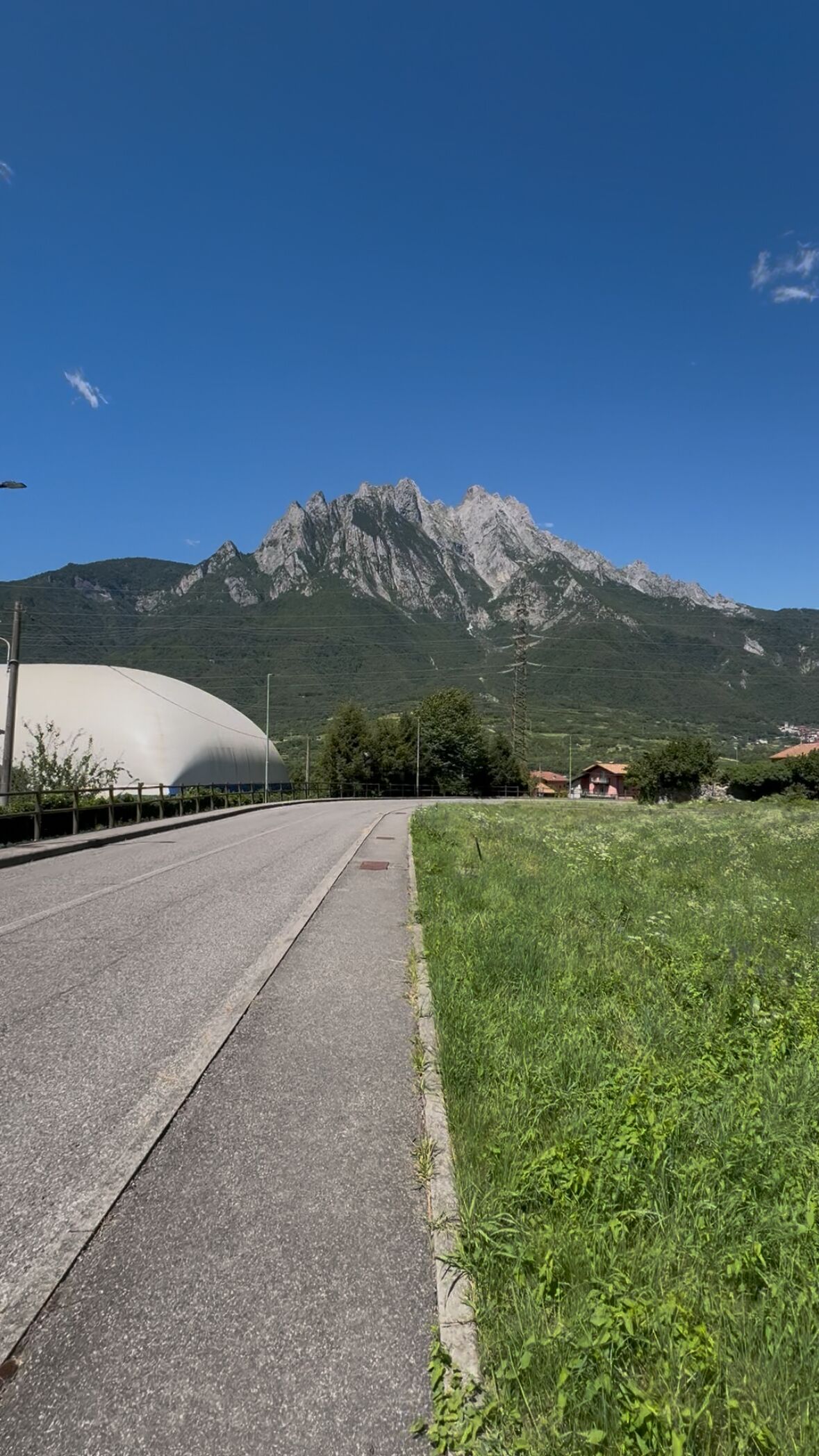 Eine Straße führt zu einem weißen, kuppelartigen Gebäude, im Hintergrund ein Gebirge.