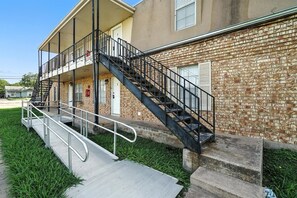 A building with a brick facade, a balcony, and a staircase leading to the entrance.