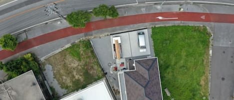 An aerial view of a building with a flat roof, a parking area, and a red pathway.