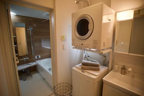 A compact bathroom with a built-in washing machine, a small sink, and a mirror. - kafuya tsukishiro (Nanjo)