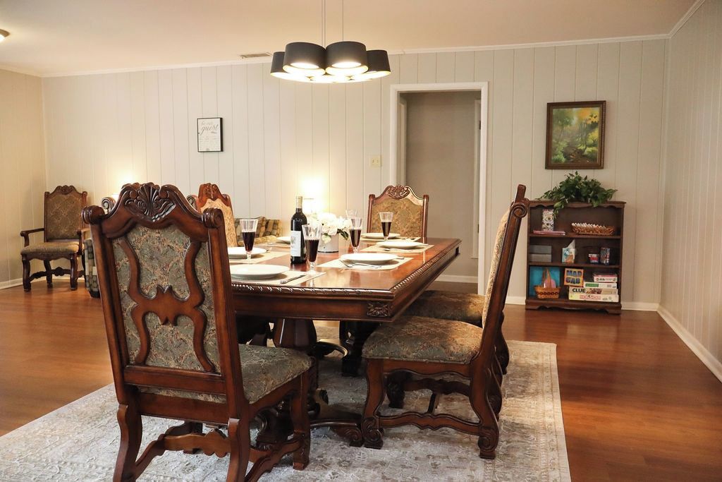 Comedor con una mesa de madera dispuesta para cuatro personas, rodeada de sillas tapizadas con diseños elaborados.
