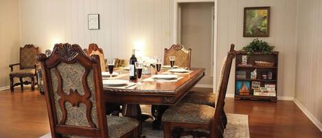 Comedor con una mesa de madera dispuesta para cuatro personas, rodeada de sillas tapizadas con diseños elaborados.