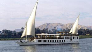 A boat with two sails, a covered deck, and a mountainous backdrop. - Dahabeya Farouz El Nil 3 (Al Bairat)