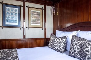 Una habitación con cabecera de madera, cama con ropa de cama estampada y dos adornos enmarcados en la pared.
