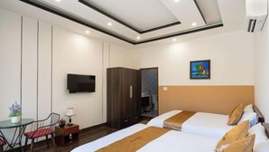 Habitación de hotel con dos camas, un televisor, un escritorio con una silla y un armario.