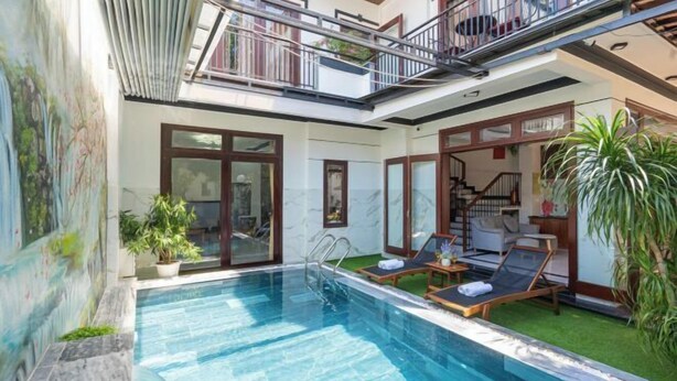 Una piscina con sillas de descanso, una escalera y un balcón.