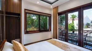 Habitación de hotel con cama, ventana con vistas a la vegetación y un armario de madera.