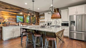 A modern kitchen with a large island, stainless steel appliances, and a rustic wooden accent wall.