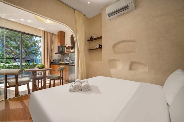 A hotel room with a bed, a dining area, and a view of the outdoors. - Bullani-sabi Hotel & Apartment (Da Nang)