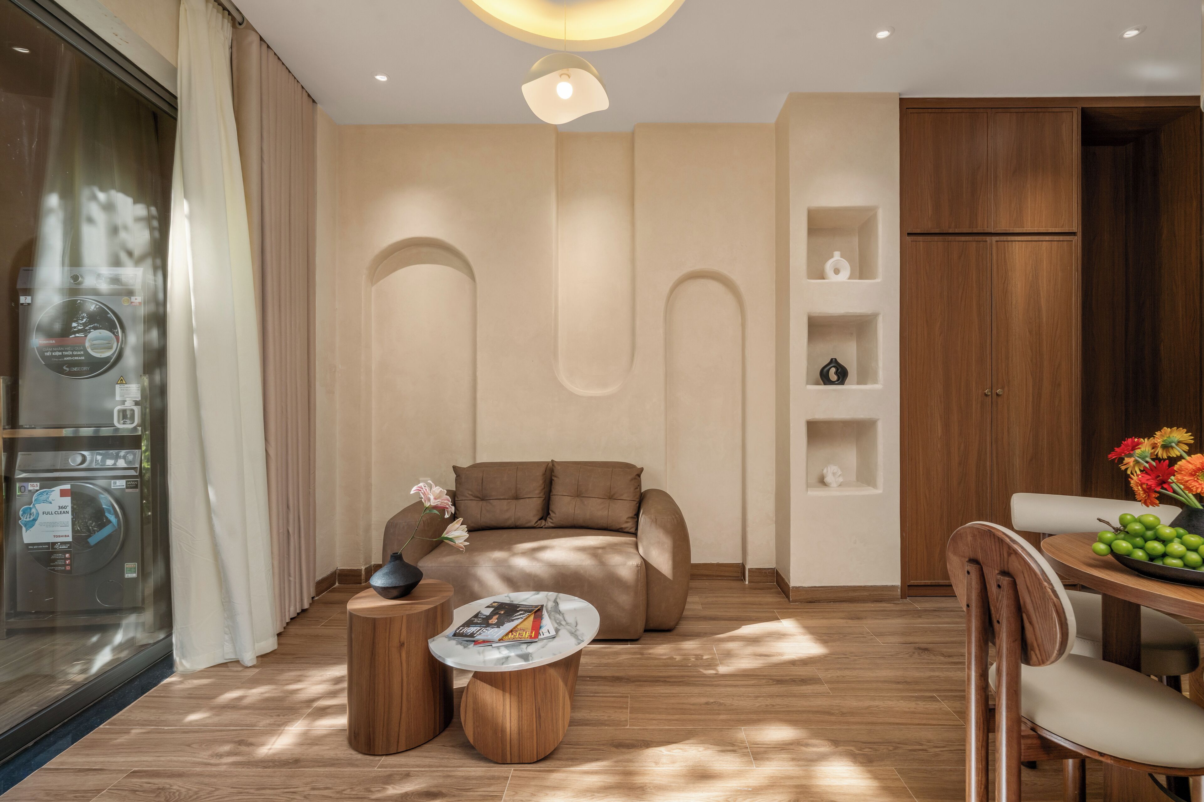 A modern living room with a sofa, two side tables, a dining table with chairs, and a wooden cabinet.