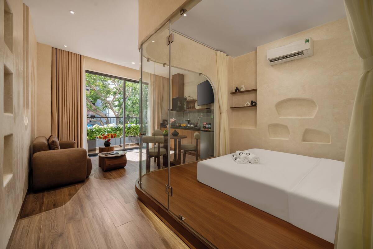 Ein modernes Hotelzimmer mit einem großen Bett, einer Couch, einer Glastrennwand, einem Essbereich und einer Klimaanlage.