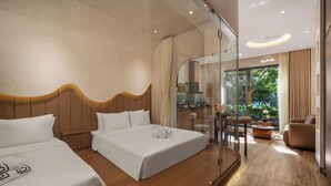 Une chambre d’hôtel moderne avec deux lits, une douche en verre, un coin salon avec un canapé et des fauteuils, et une vue sur l’extérieur.