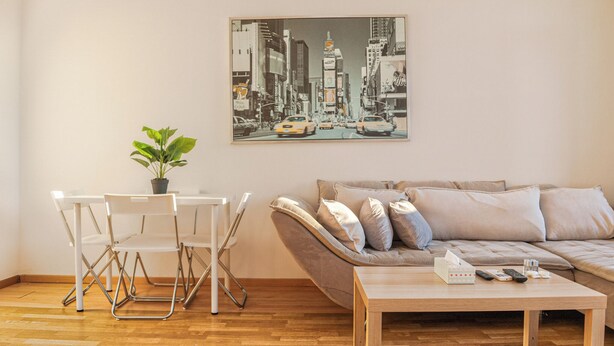 A living room with a sofa, a coffee table, and a dining area with chairs and a table. - Charming 2BR Apt in Prime Location (Vienna)