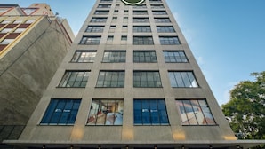 A tall building with multiple windows and a prominent logo at the top. - Stunning 1 BR Condo - Downtown - Alameda Central (Mexico City)