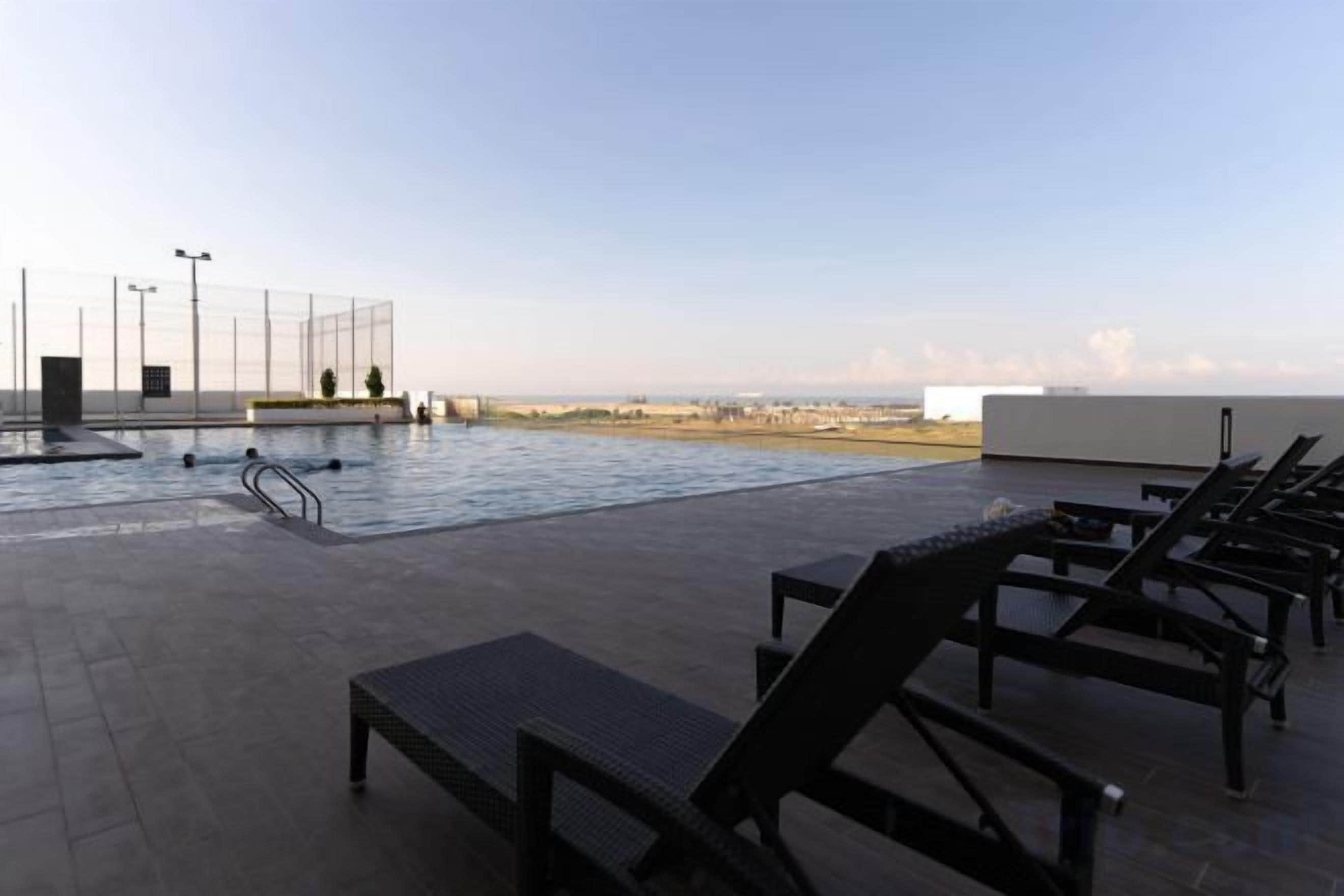 An outdoor swimming pool with lounge chairs and a view of the beach.