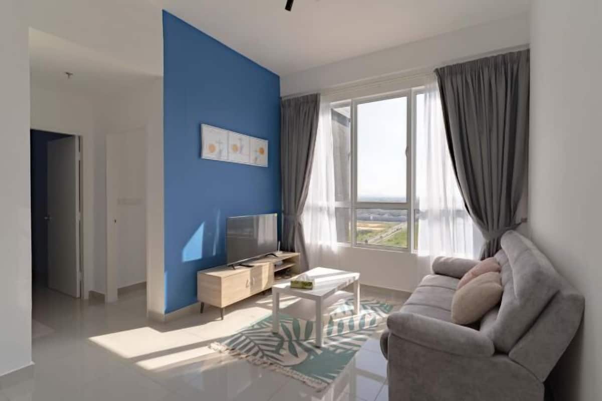 Uma sala de estar moderna com uma parede azul de destaque, uma TV de tela plana, um sofá, uma mesa de centro e vista através de uma grande janela.