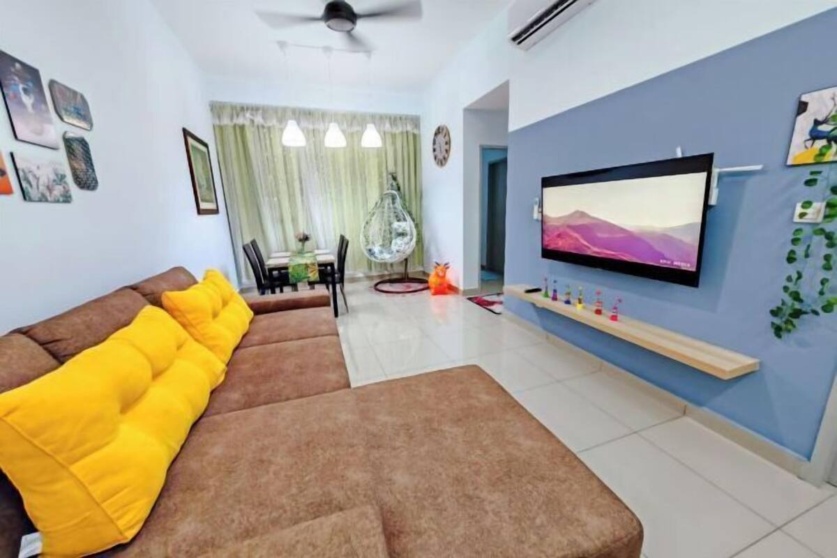 Uma sala de estar com sofá, televisão e um espaço de jantar com mesa e cadeiras.