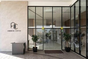 A modern hotel entrance with glass doors, a reception desk, and potted plants. - Amber Cove Impression City Melaka by Dawn Stay Free Netflix (Melaka Tengah)