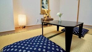 A room with tatami flooring, a low table, a lamp, and a painting on the wall. - Nenenomichi (Kyoto)