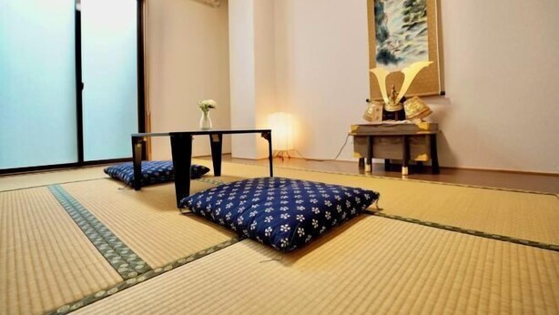 A tatami mat room with a low table, cushions, and a painting on the wall. - Nenenomichi (Kyoto)