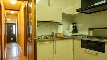 A kitchen with a stove, coffee maker, and cabinets.