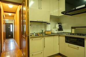 Een keuken met een fornuis, koffiezetapparaat en kastjes.