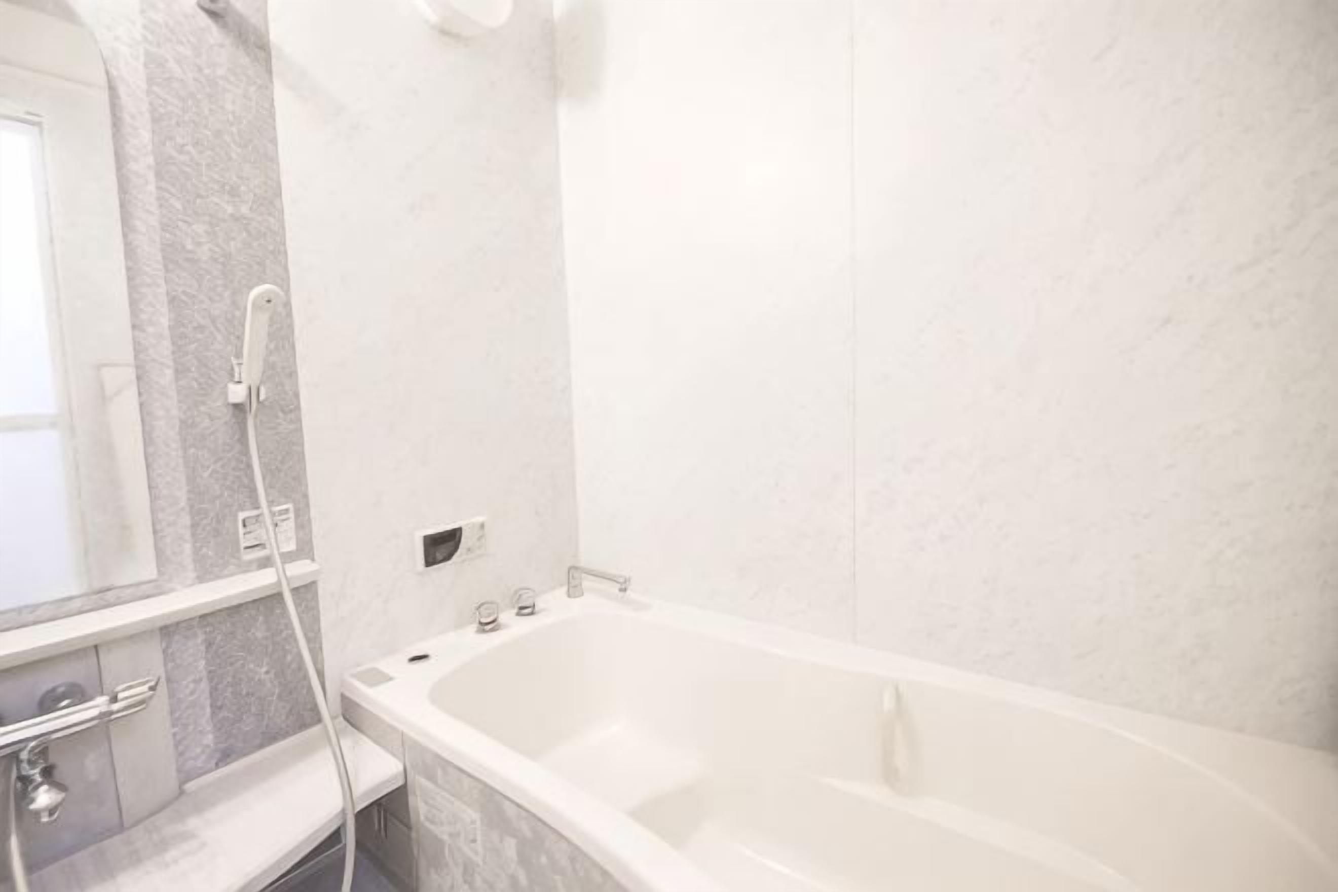 A bathroom with a bathtub, a shower, a mirror, and a marble wall.