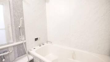 A bathroom with a bathtub, a shower, a mirror, and a marble wall.