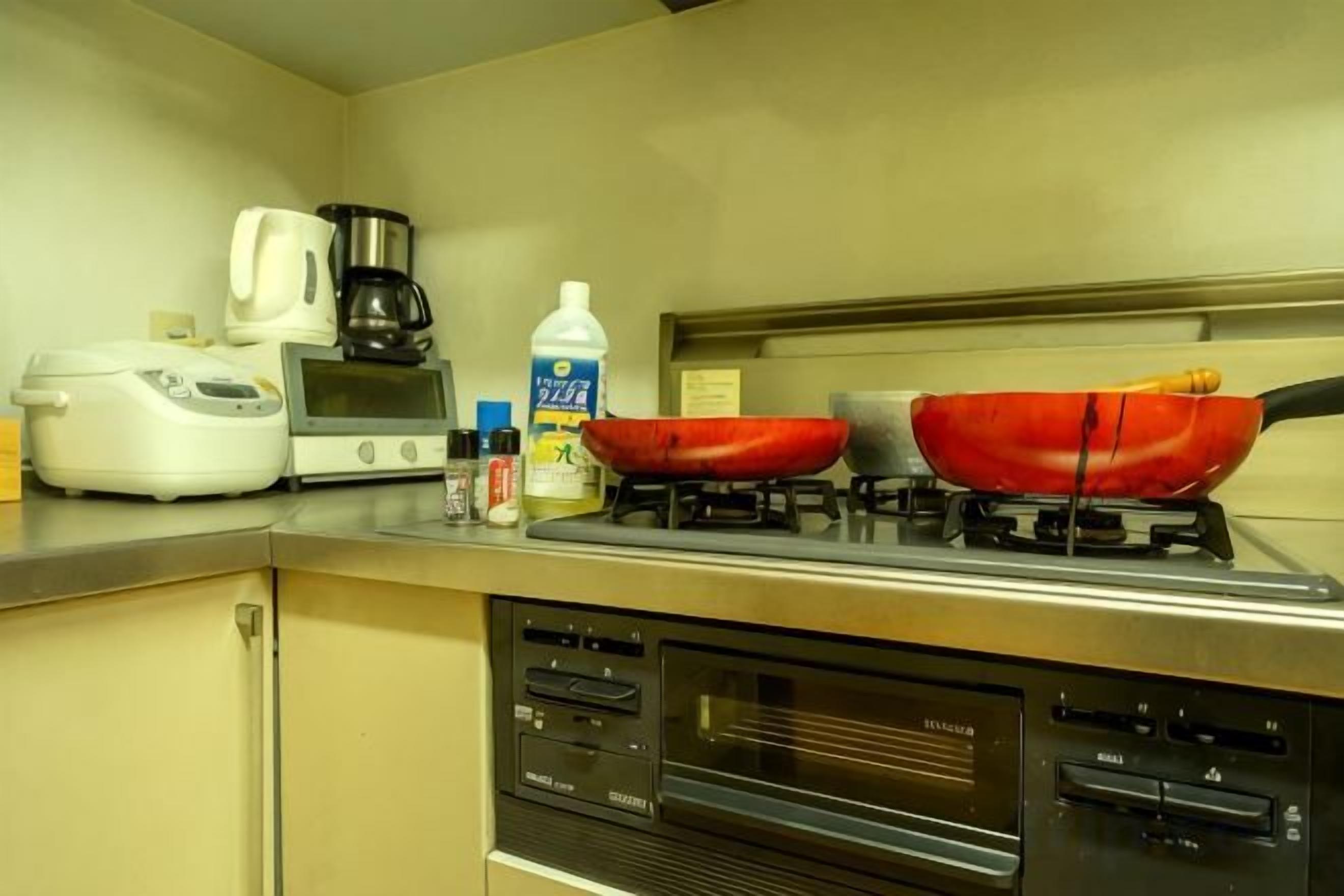 A kitchen with a gas stove, a coffee maker, a rice cooker, and a microwave.