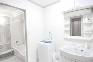 A bathroom with a bathtub, a sink, and a mirror. - Tolai ryokan 1gokan (Atami)