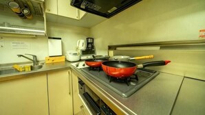 Een keuken met een magnetron, fornuis en twee rode pannen.