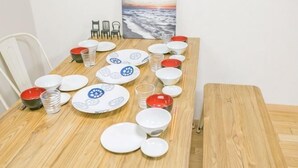 Een eettafel gedekt met borden, glazen en stokjes, met stoelen en een schilderij aan de muur.