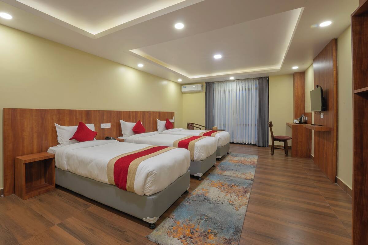 A hotel room with two beds, a desk, a chair, and a television.