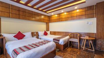 A hotel room with two beds, a wooden headboard, a small round table, and a chair.