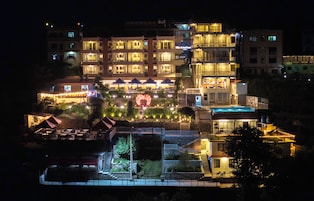 Un hotel de varios pisos con áreas de estar al aire libre y un elemento decorativo central.