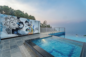 Una piscina con un mural en la pared contigua, un suelo de baldosas y vistas al mar.