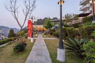 Un sendero que conduce a un edificio con jardín, escaleras y mobiliario exterior.